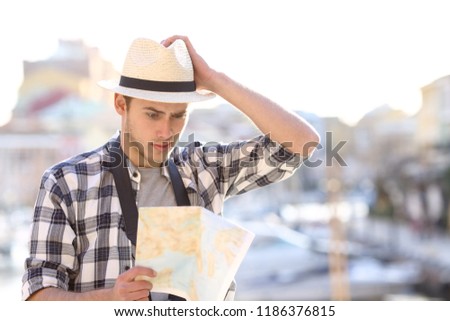 Lost tourist consulting a confusing guide in a coast town street on vacation