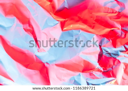 Crushed paper background in vibrant bold gradient holographic neon colors. Fire background imitation. Flat lay. Top view.