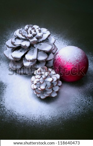 Pine cones on snow with a red Christmas balls