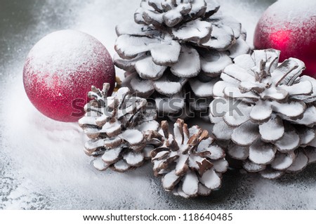 Pine cones with two red Christmas balls and snow
