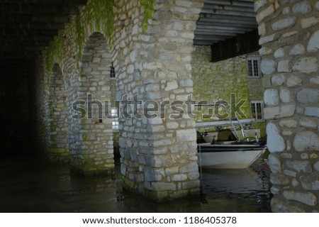 Old Dark Mossy Stone Archways in a Lake Boathouse