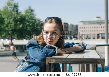 Close up portrait of a young woman sitting at the table in a street cafe on a warm sunny day