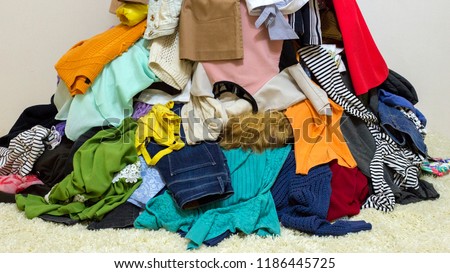 Different colored clothes background. Mixed up dresses, jeans, skirts and other used clothes Royalty-Free Stock Photo #1186445725