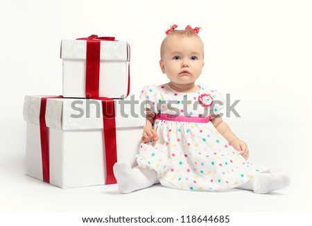 Adorable baby girl with two gift boxes posing over white background