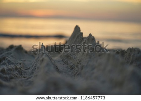 miniature mountains of sand on the beach against the backdrop of the setting sun