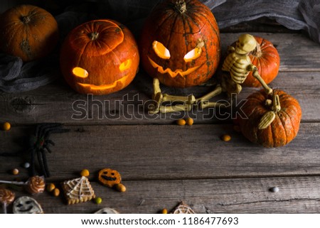 happy halloween pumpkins with glowing eyes, spiders, horror stories and more on a wooden background