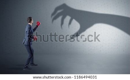 Tiny businessman fighting with scary hand shadow