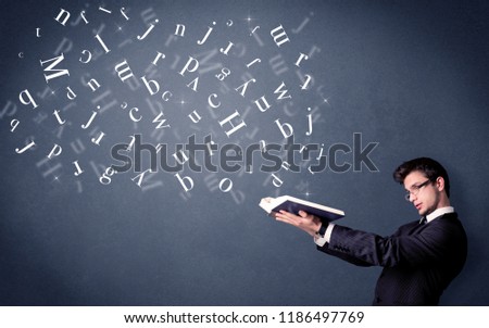 Casual young man holding book with white letters flying out of it