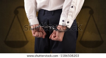 Arrested businessman in handcuffs with hands behind back and justice symbol wallpaper