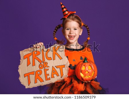 happy Halloween! cheerful child girl in costume with pumpkins on a violet purple background

