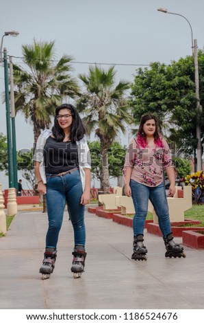 Two chubby girls with inline skates in the park happy