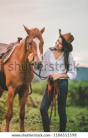 Asian young woman  take care of her brows horse at sunset.