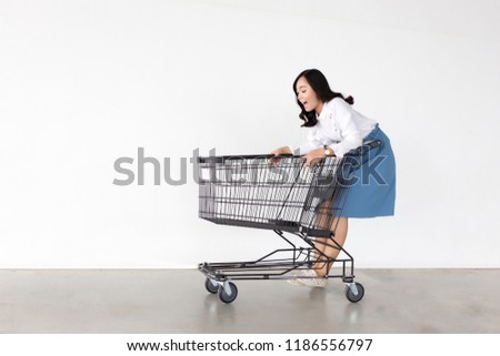 happy asian lady in shopping action with shopping cart on white background.