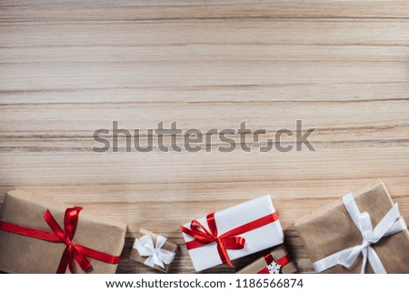 Border of gift boxes on wooden background. Christmas composition. Top view, flat lay. Mock up, copy space for your text.
