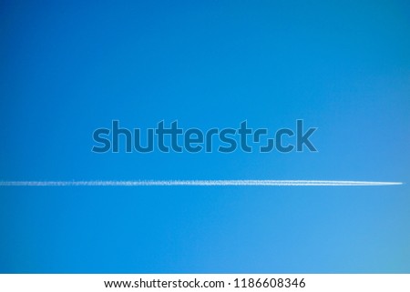 An aircraft leave a vapor trail on blue sky background