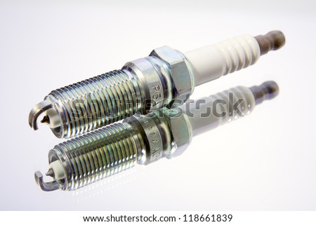 Close up of a spark plug on white glass surface
