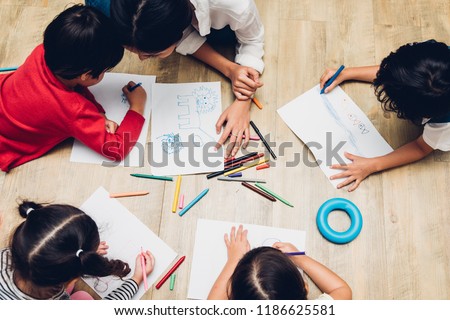 Top view Family happy children group kid boy and girl kindergarten paint drawing on peper with teacher education together at interior playroom