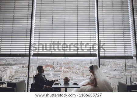 The stylish and elegant bridegroom and his pretty wife sitting in a restaurant
