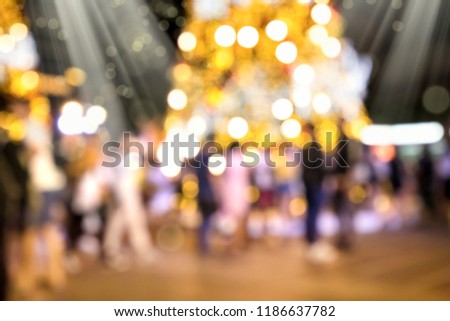 Conceptual defocused Christmas decoration and crowd of people on city street at night