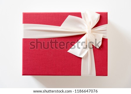 red giftbox with white bow strip on white background , top view
