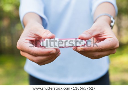 Close up picture of happy young woman holding pregnancy test outdoor