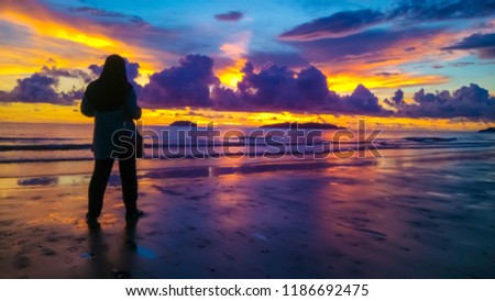 women taking picture at the beach during sunset.
