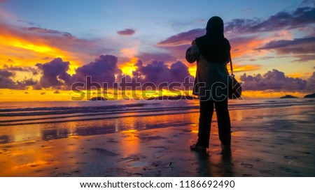 women taking picture at the beach during sunset.