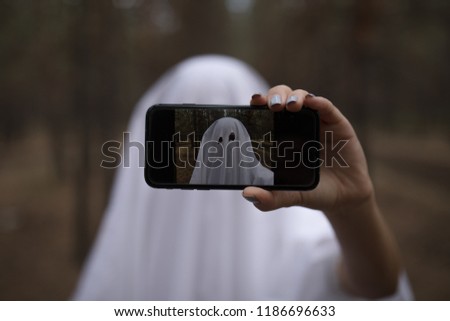 Woman in halloween ghost costume make selfie in the forest.