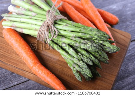 Freshly picked carrots and asparagus on wood background