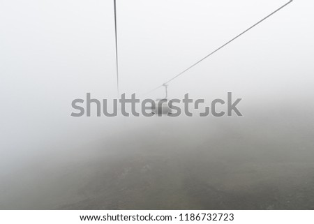 empty chairlift and cable in a bleak and foggy mountain landscape in the early autumn in a ski resort in Switzerland