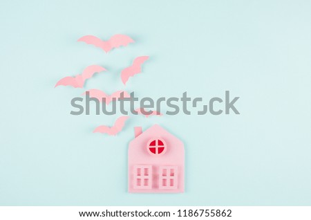 Halloween background - pink house and flock fly bats as cut cartoon on pastel mint blue paper background.