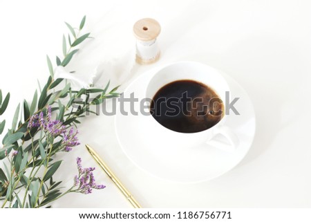 Wedding styled stock photo. Breakfast still life with eucalyptus leaves, limonium, baby's breath Gypsophila flowers, golden pen, cup of coffee and silk ribbon. Floral composition. Selective focus.