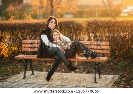 Mother and little daughter is sitting on a bench in the park