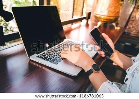 Young woman working on laptop computer on the wooden desk at Coffee shop, vintage tone.Bussiness concept background,