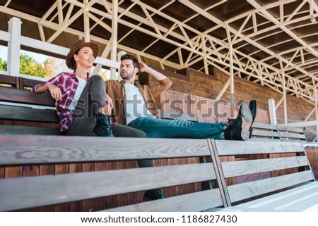 colleagues in casual clothes sitting on bench at ranch stadium
