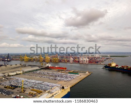 Aerial view of logistics concept floating dry dock servicing cargo ship and commercial vehicles, cars and pickup trucks waiting to be load on to a roll-on/roll-off car carrier ship at Laem Chabang