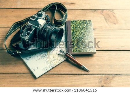 Travel concept. Camera, map, notebook and ball pen on wooden table