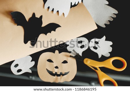 Halloween crafts. Ghosts, pumpkins, bats, spider, scissors and stationery knife. Top view. Flat lay.