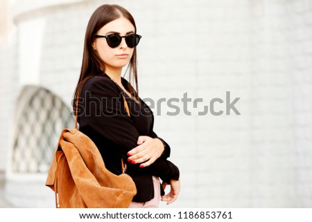Beautiful young student hipster girl with healthy straight hair wearing a black jacket, sunglasses and backpack. Street style. Photo toned style instagram filters