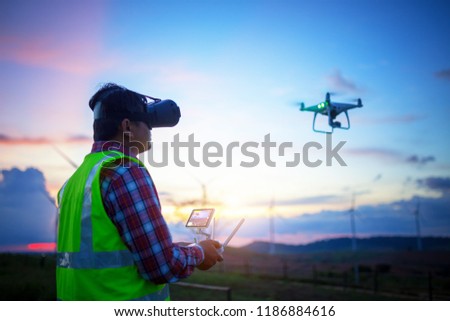 Engineer operate Drone flying for survey construction wind farm on sunset.