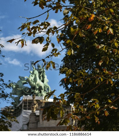 Picture of a tree with a statue in the background. Taken in Paris, France, next to the "petit palais". 