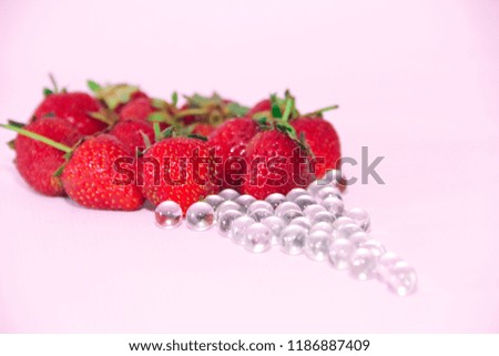  red strawberries and glass balls on a pink background
