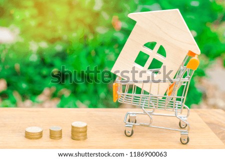 Wooden house in a Supermarket trolley. Property investment and house mortgage financial concept. buying, renting and selling apartments. real estate. saving money