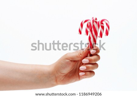 Lollipops of red and white color in a female hand on a white background