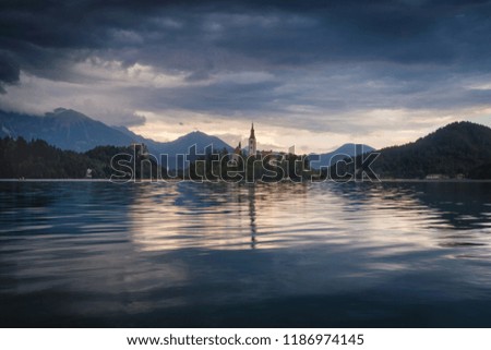 Amazing View On Bled Lake on Sunset. Europe. View on Island with Catholic Church in Bled Lake with Castle and yellow sky on the Background.