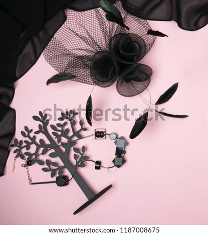 top view Halloween party collection female outfit accessories black on light pink background: jewelry, hat with veil and feather. Flat lay, top view, copy space. Black Friday concept