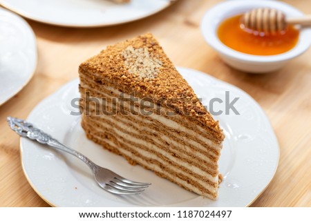 Slice of layered honey cake. Russian cake Medovik with walnuts. Royalty-Free Stock Photo #1187024497