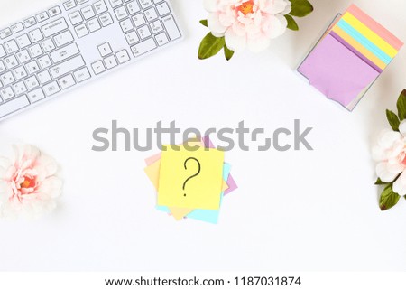 Multicolored stickers note with question mark on white desktop next to a mug of coffee and keyboard.