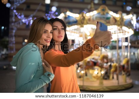 Girls take a selfie, women make mobile photos using smart phone at nigth city