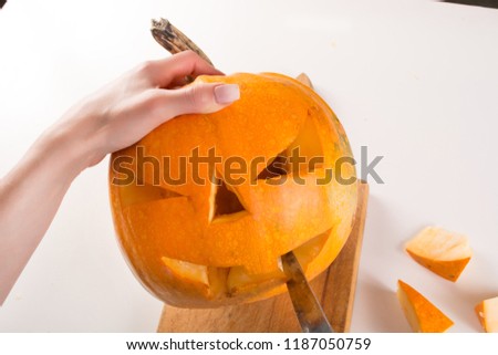 Carving orange pumpkin for Halloween holiday. Girl hand with knife cuts and prepare jack o lanterns. Close up, selective focus